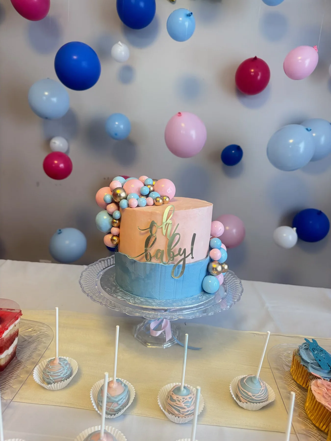 Birthday dessert table with a blue number cake and a colorful balloon wall